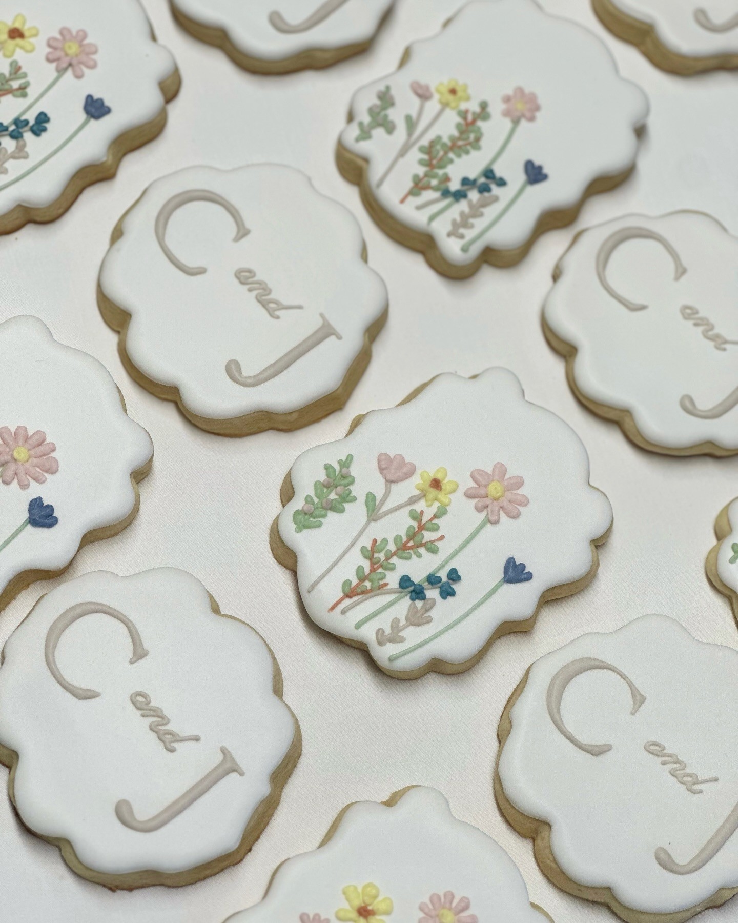 C and J wedding cookies — cream scalloped cookies with delicate watercolor wildflowers and elegant monogram lettering